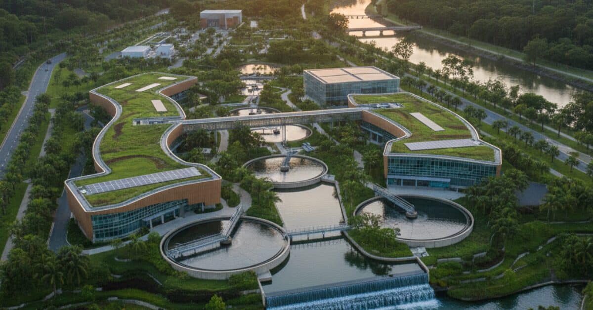 لقطة علوية لمنشأة معالجة مستدامة ذات أسطح خضراء تضم أحواض ترسيب وتقنيات حديثة ضمن أنظمة معالجة المياه المتكاملة.